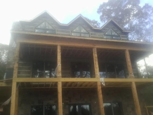 Dormers and porch framing on a large log home under construction — Roof Coating work by our crew in Sanibel