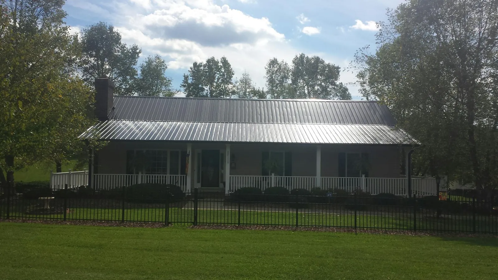 Gray metal roof on a brick ranch with a full width front porch — Gutter Guard Installation work by our crew in Sanibel