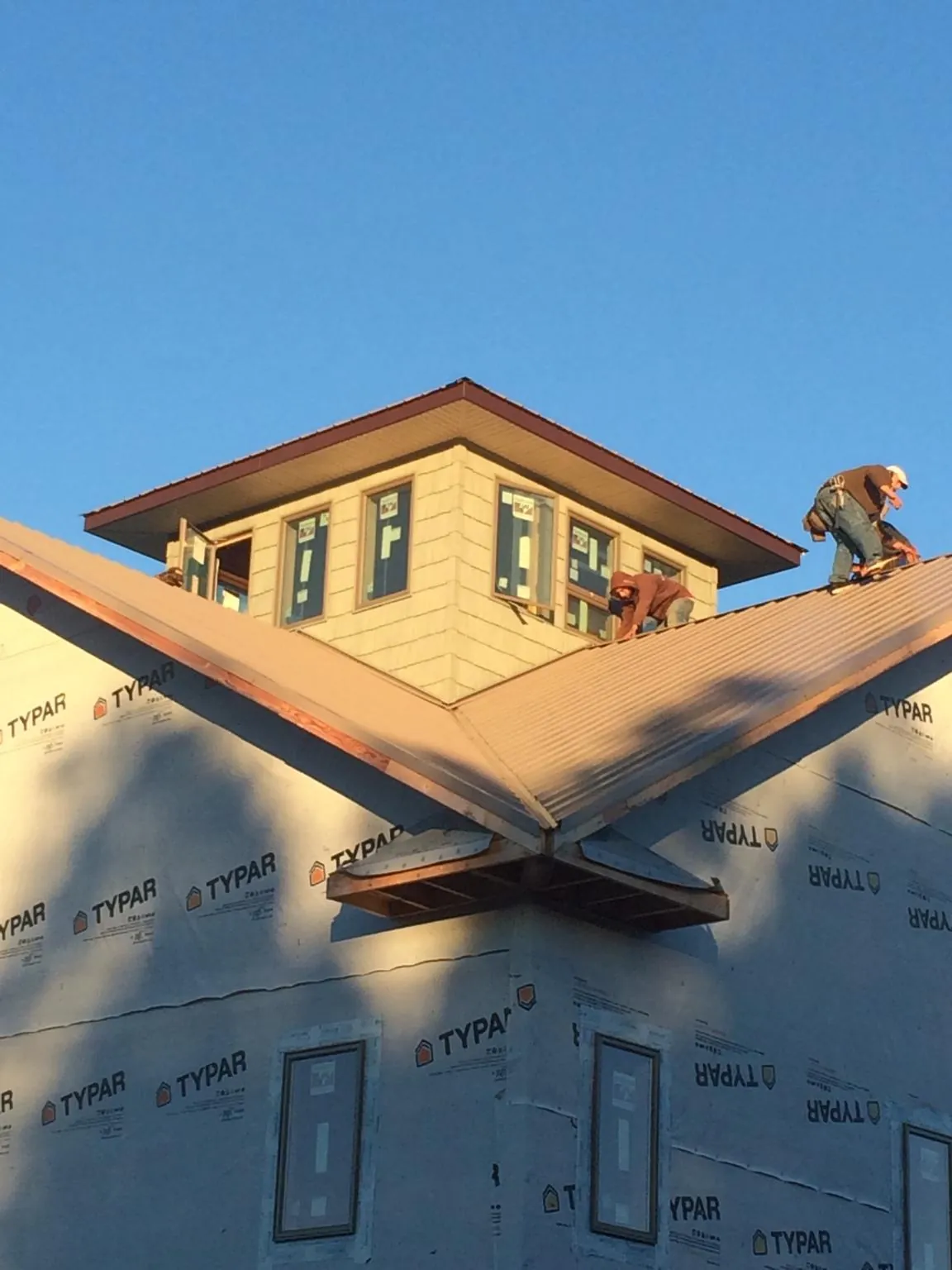 Roofers working around a rooftop cupola on a new metal roof at sunset — Roof Waterproofing in Sanibel by Roofing Brothers